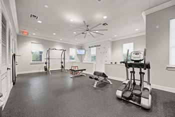 A gym with a variety of equipment including a treadmill, weights, and a bench.